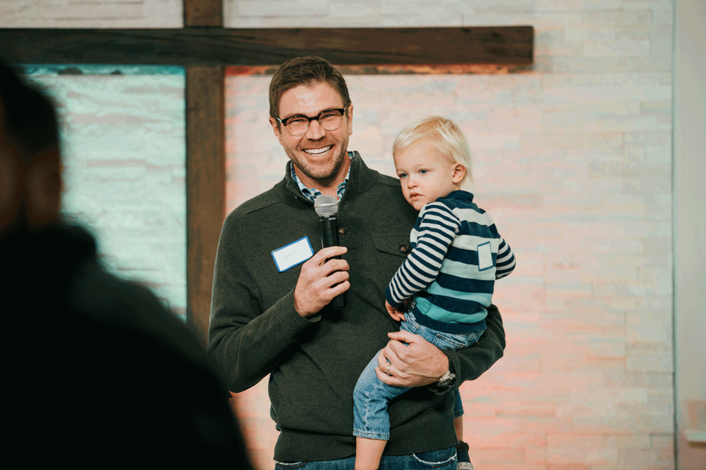 Church Elder speaking into a microphone while holding a child